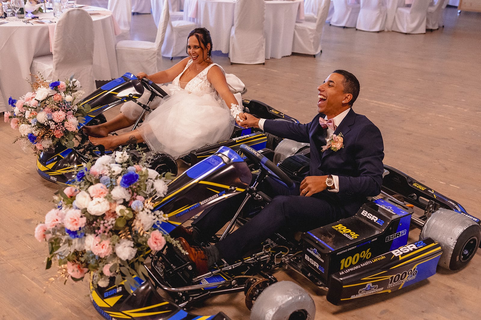 Mariés faisant une entrée originale en karts électriques décorés de fleurs lors de leur réception de mariage.